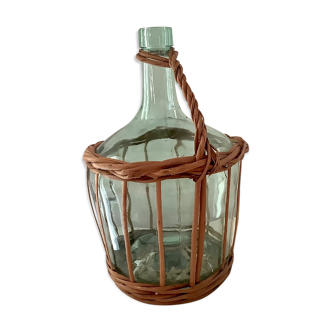 Old bottle circled with vintage rattan with handle