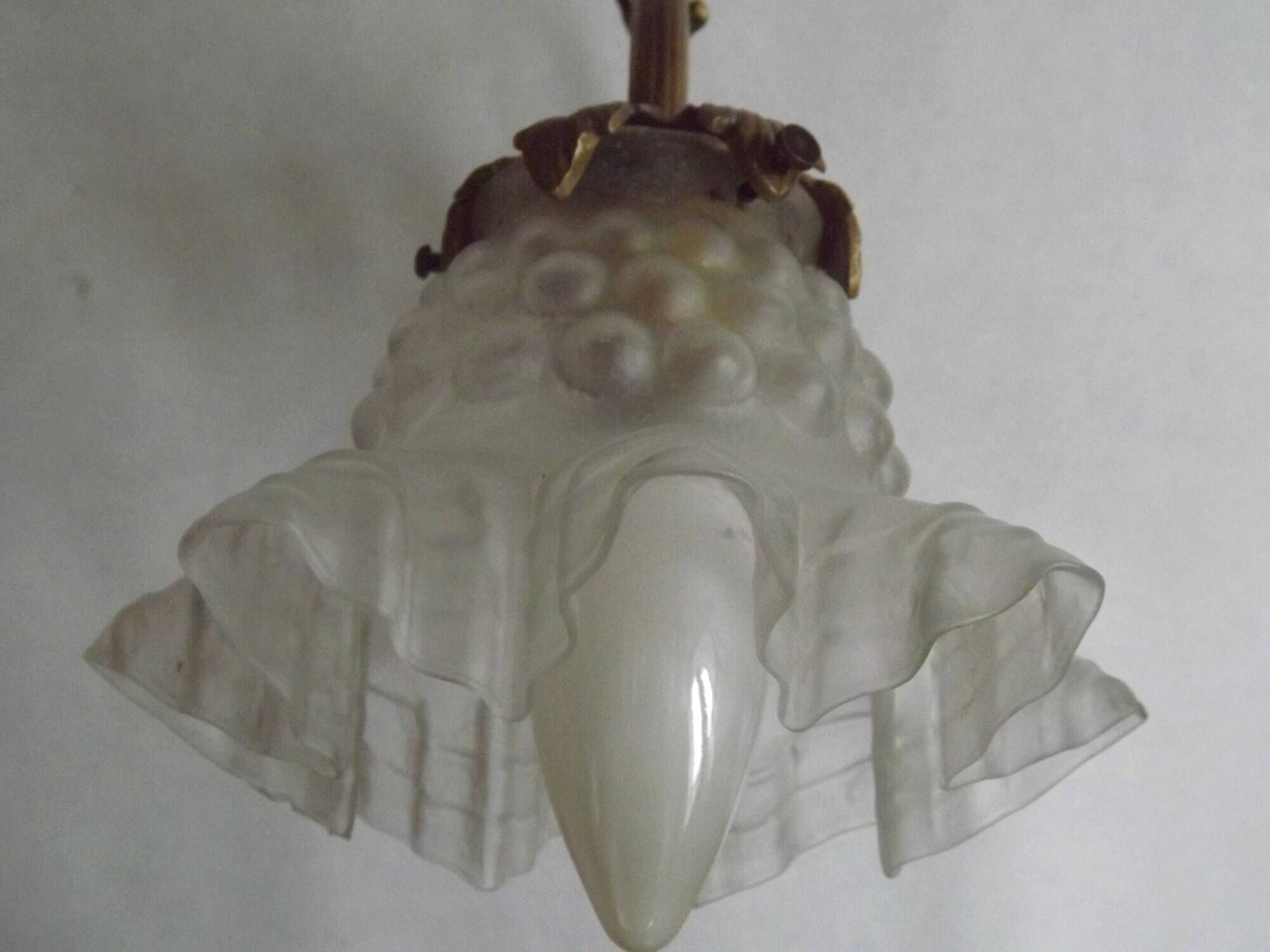 Simple wall sconce in French Art Nouveau bronze with a white glass shade featuring patterns.