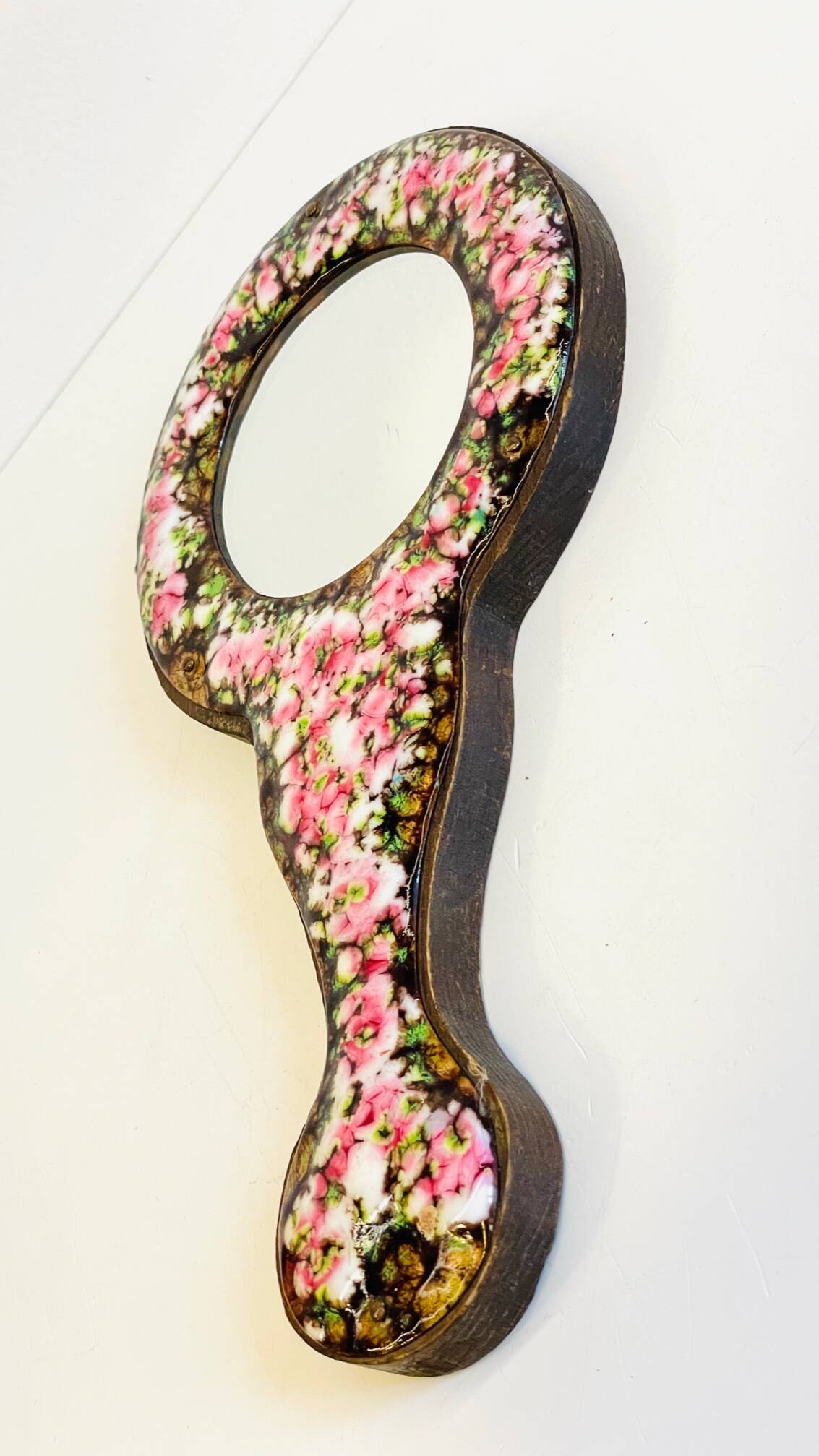 Vintage enameled metal hand mirror on wood