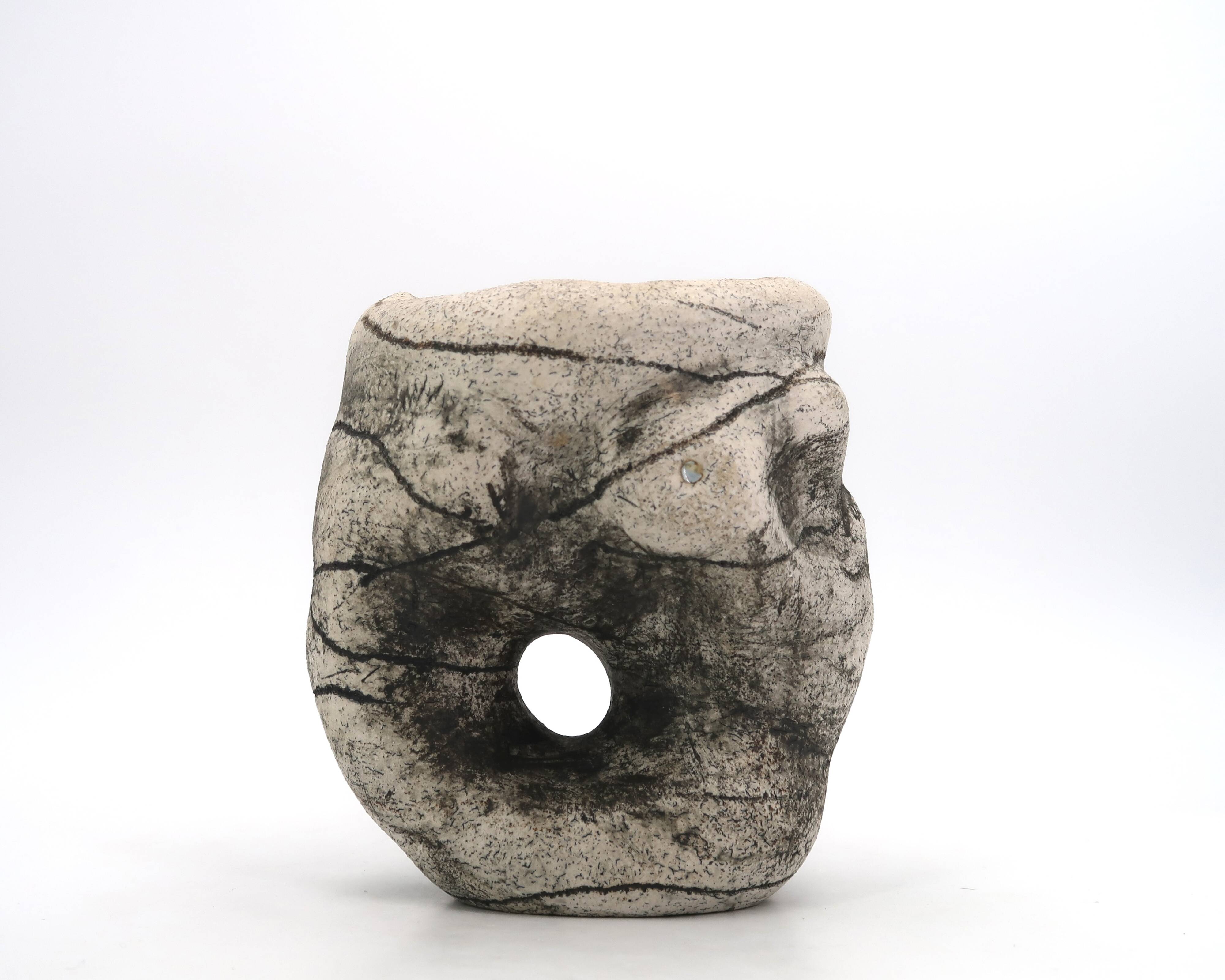 Ceramic vase sculpture decorated with faces and featuring a hole, 1980s.