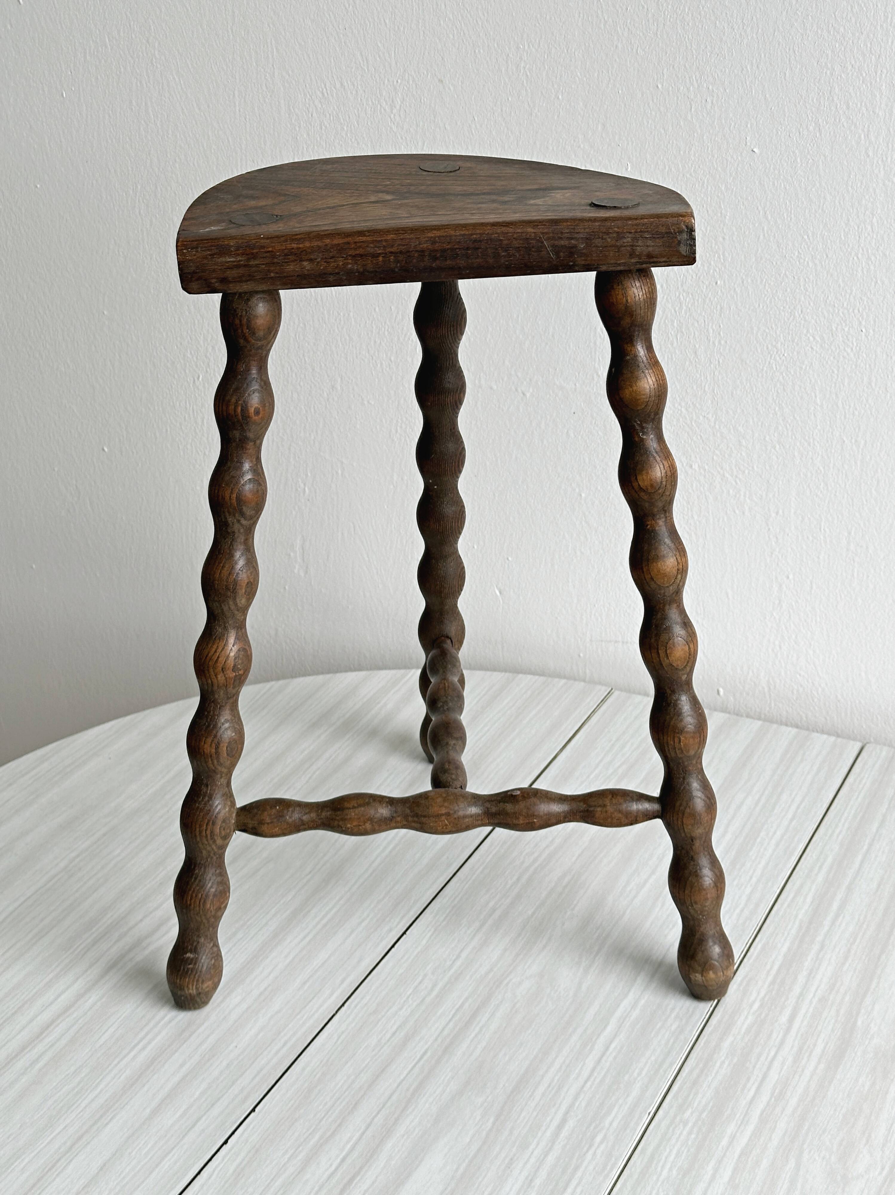 Three-legged demi-lune stool made of turned wood