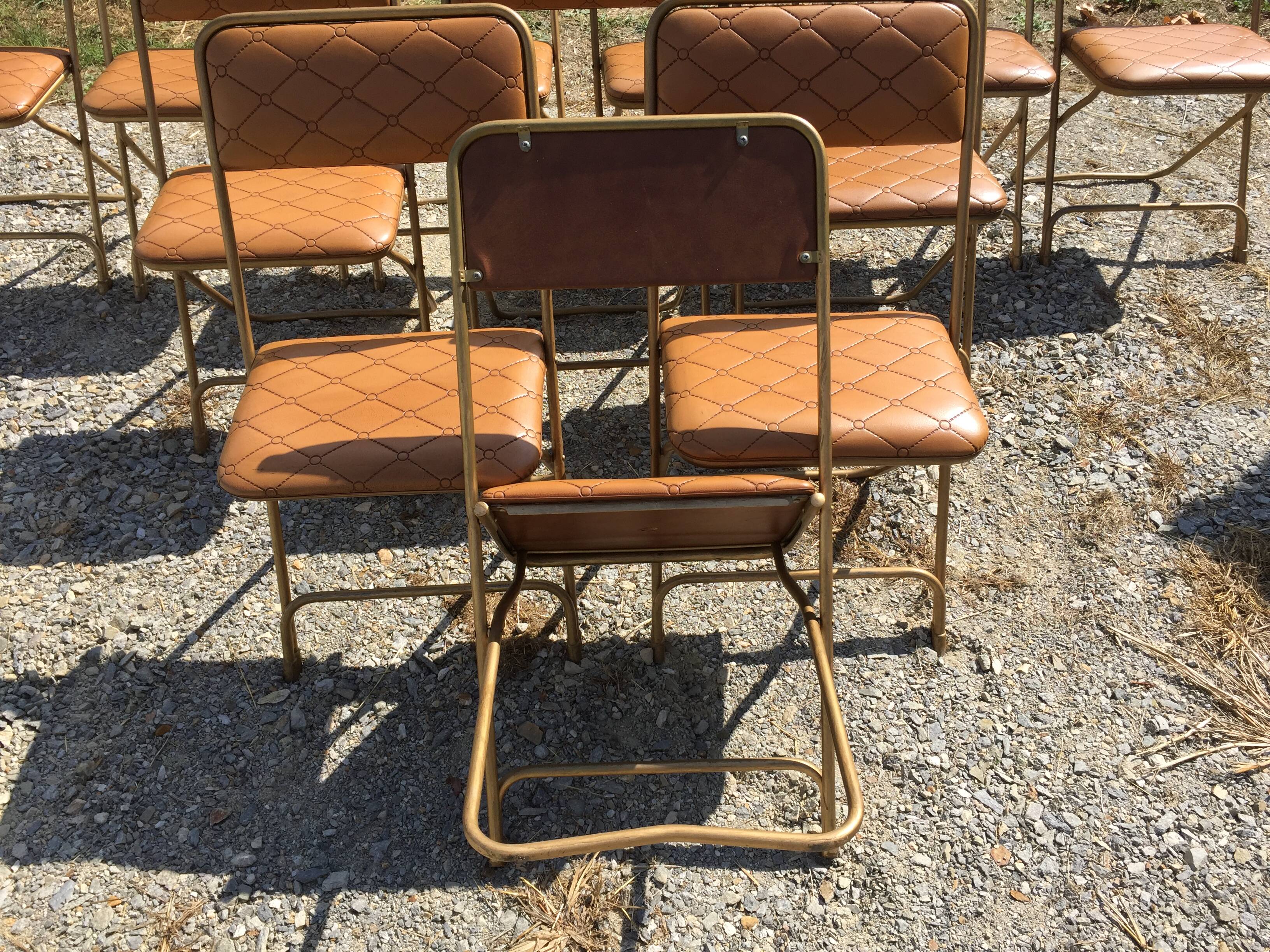 Set de 12 chaises vintage pliantes en skaï assises et dossiers matelassés à piètement tubulaire doré
