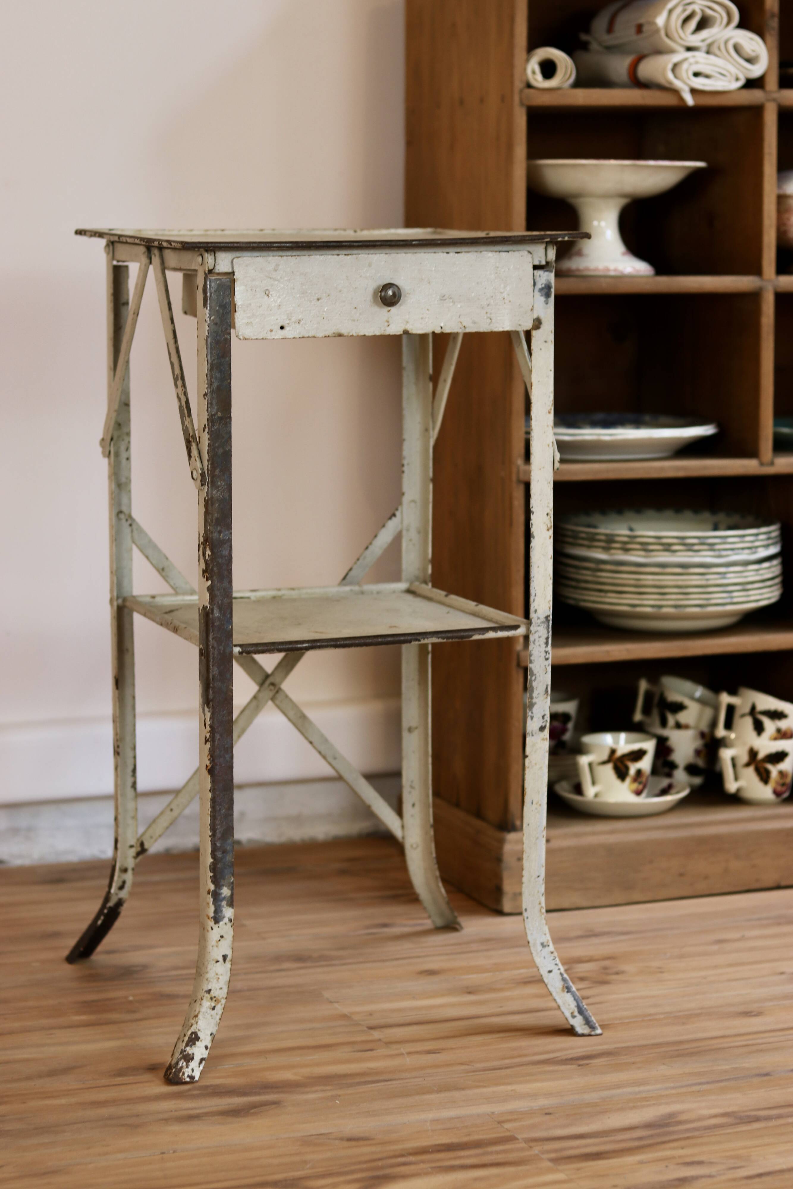 Painted metal side table, patinated white, with a drawer and two shelves