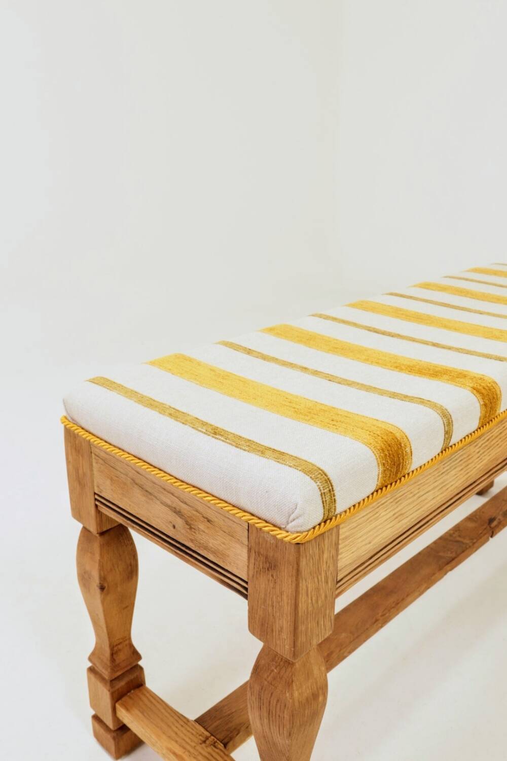 Vintage oak bench with striped linen fabric in a country style.