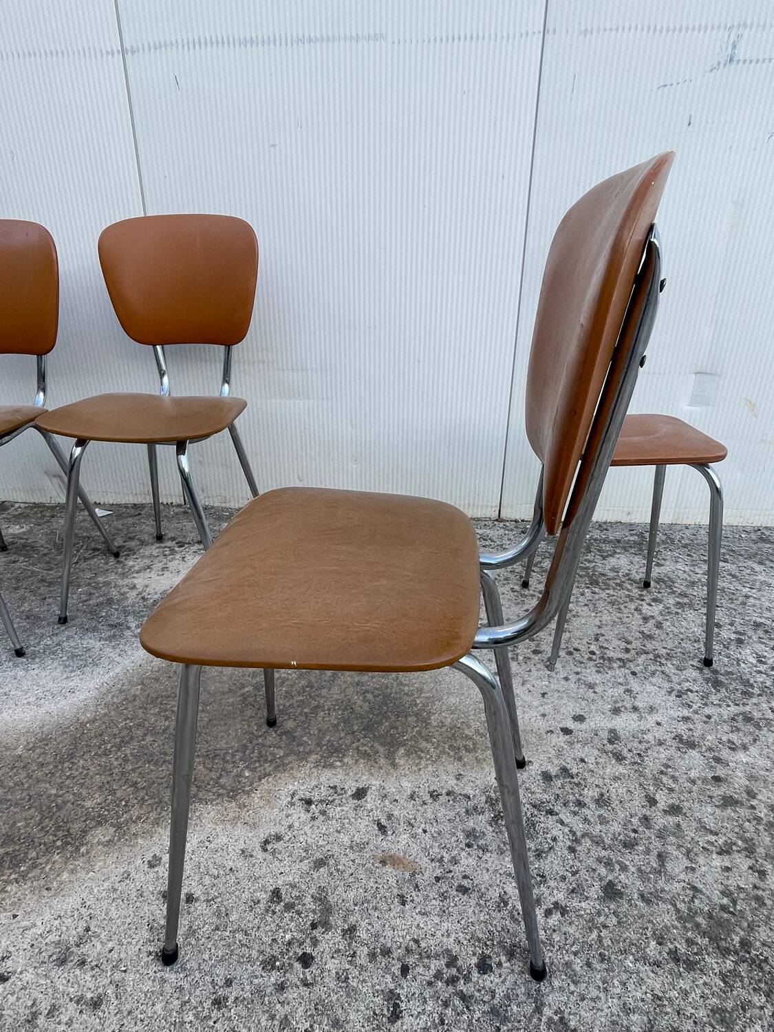 3 chairs and a vintage stool in faux leather and tubular design.