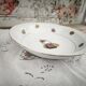 Shallow round plate in Limoges porcelain with a hydrangea basket design.