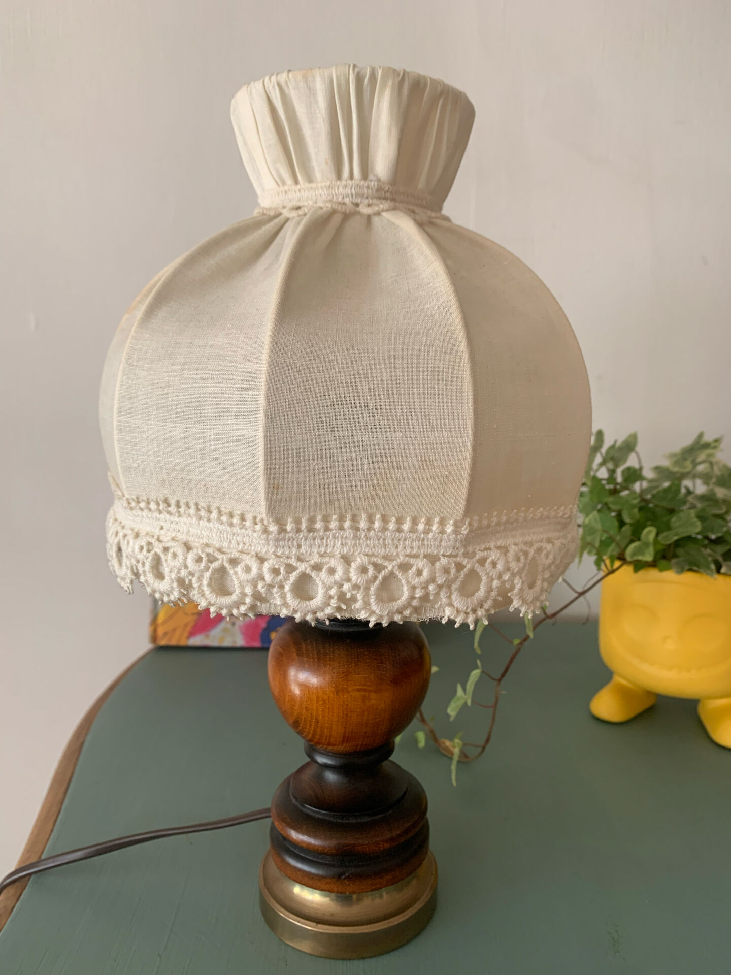 Small vintage wooden turned table lamp with a pleated shade.