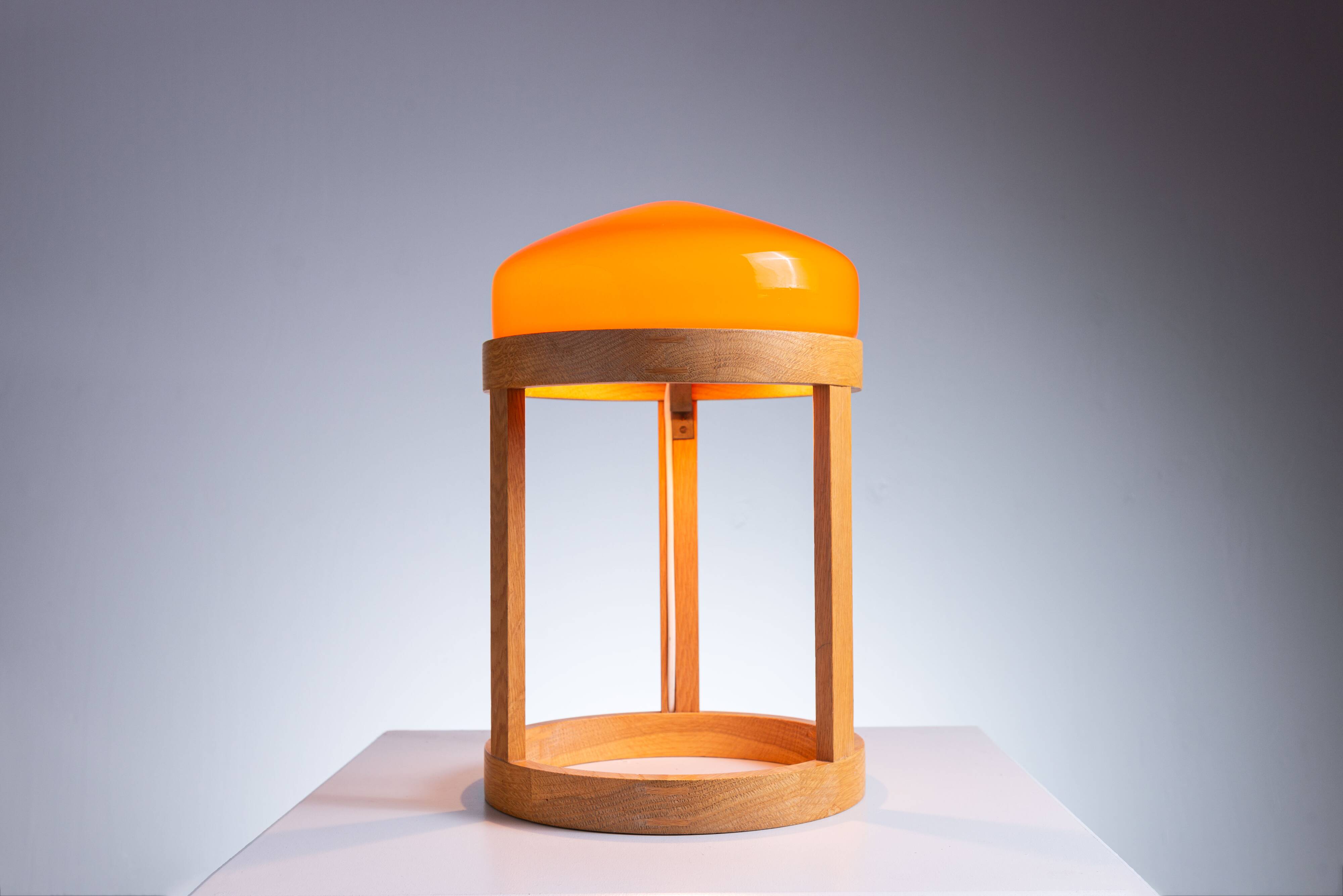 Bent oak wood table lamp with orange glass shade