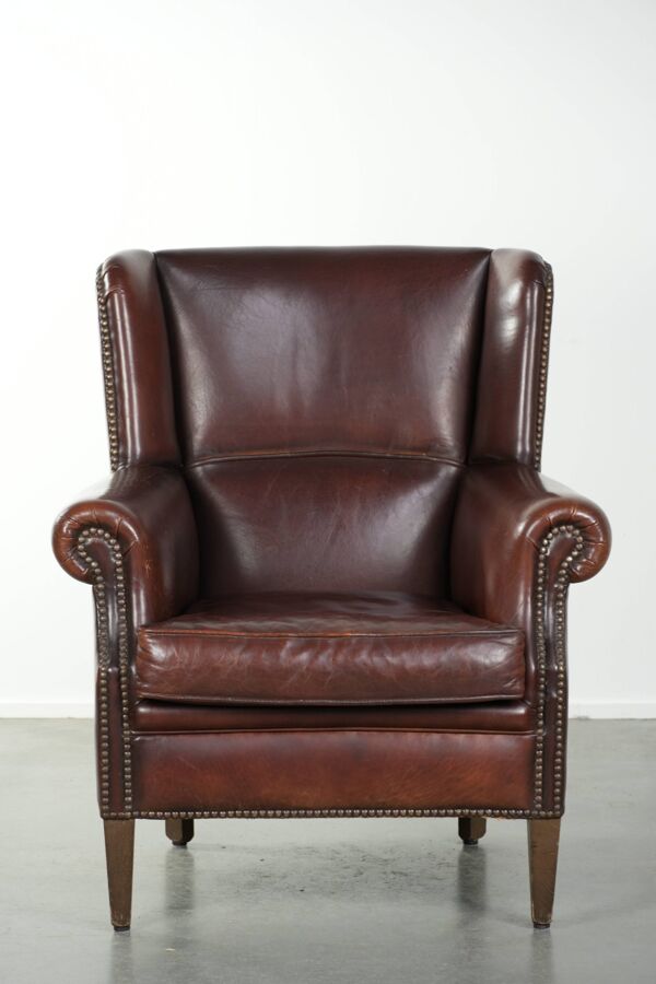 Fauteuil en peau de mouton vintage avec un dossier haut fini avec des clous décoratifs.