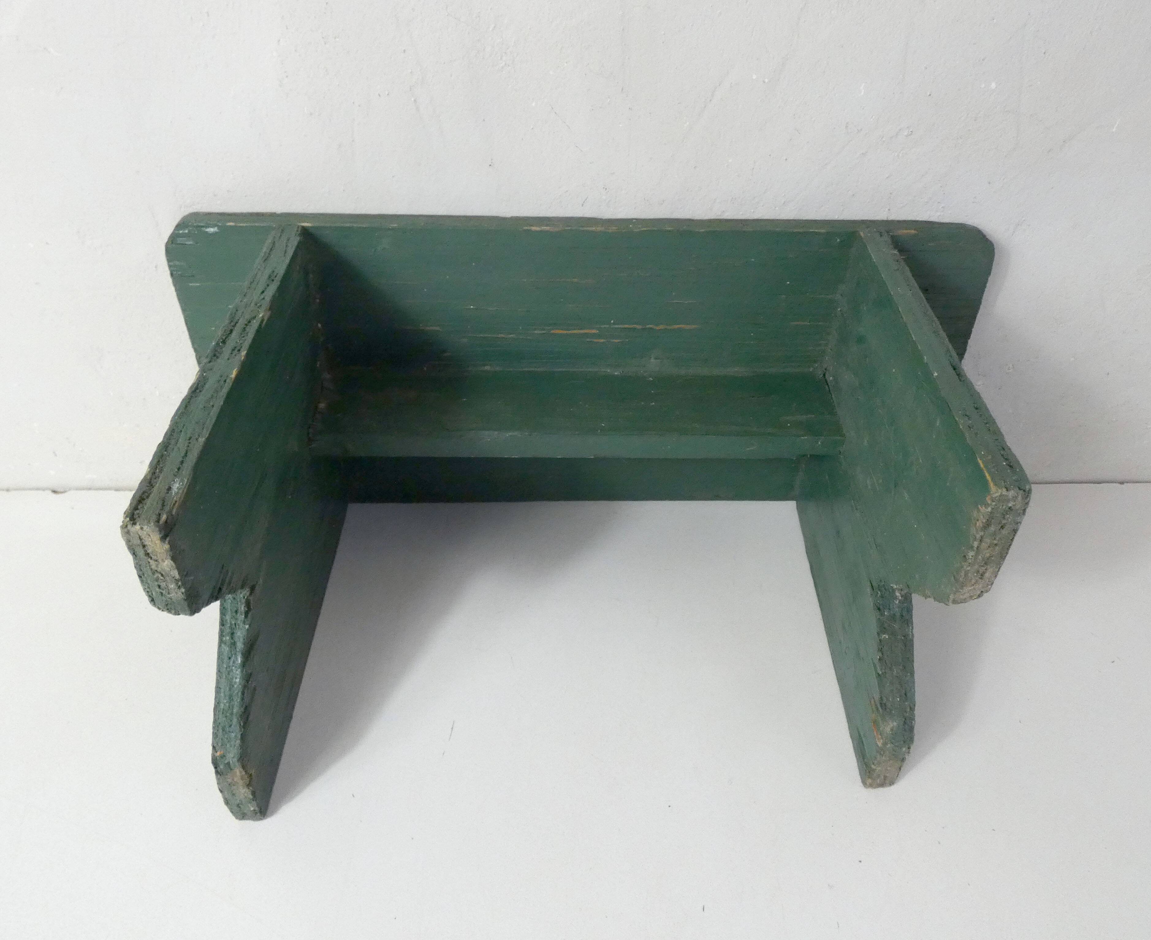 Old small wooden bench with green foot