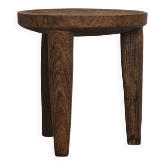 Antique stool made of raw wood carved from a single trunk