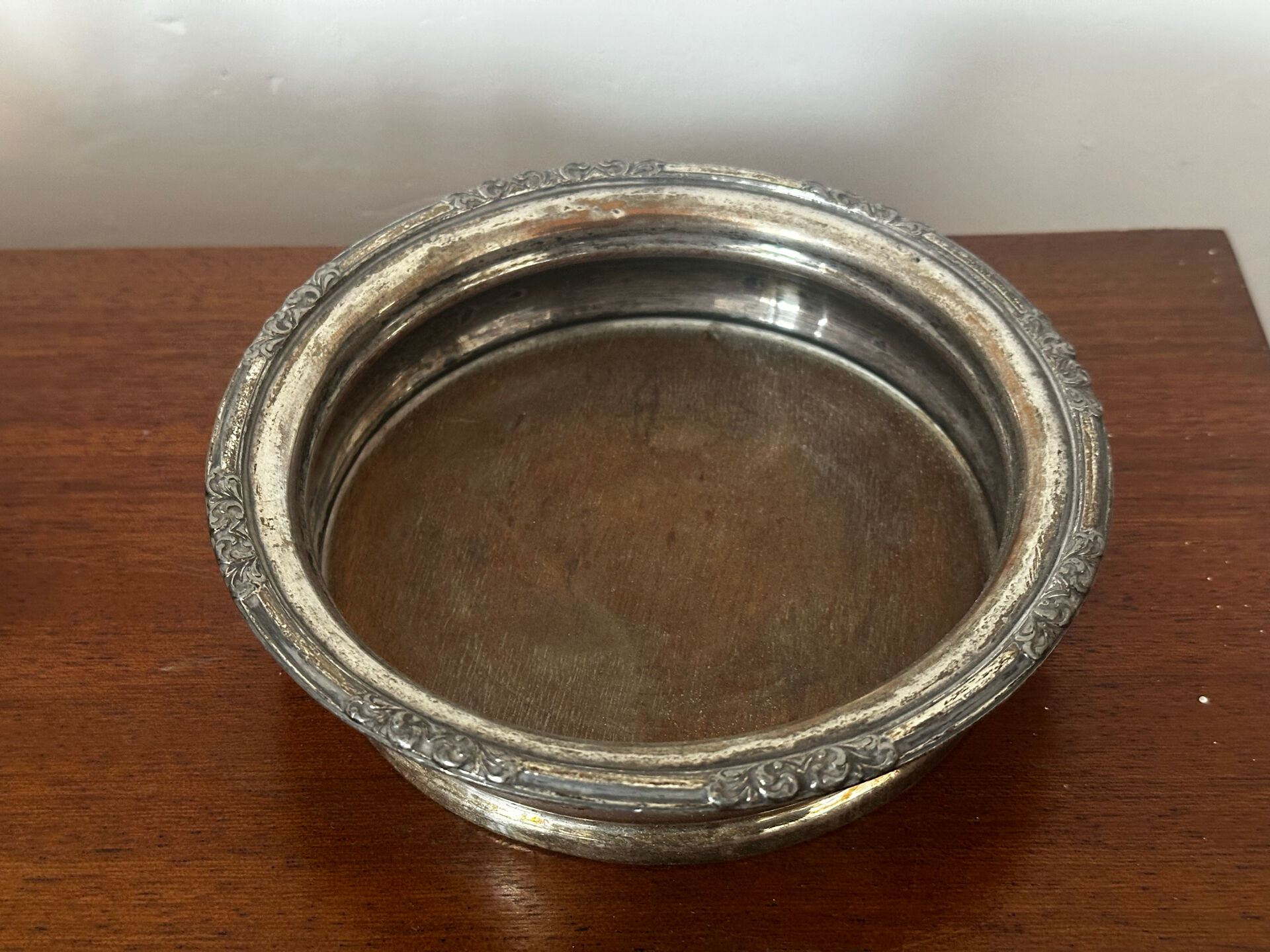 Antique silver-plated bottle coaster with floral decoration.