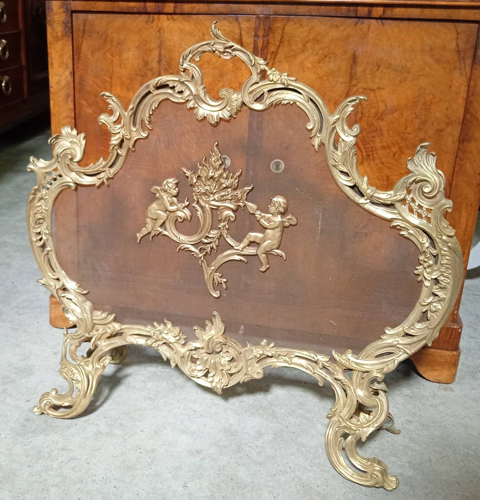 Large gilded bronze fireplace screen decorated with putti and rocaille motifs.