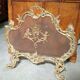 Large gilded bronze fireplace screen decorated with putti and rocaille motifs.