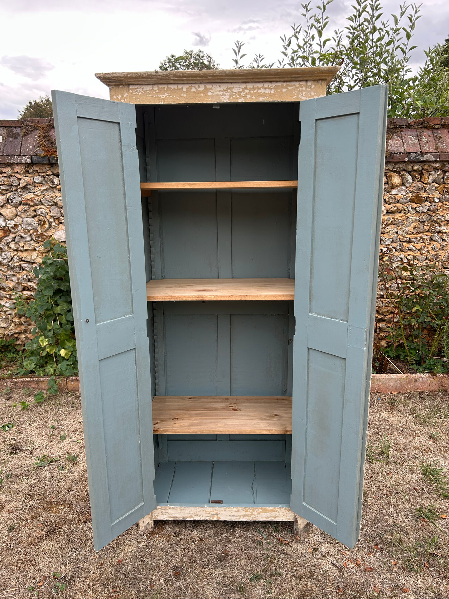 Small antique wardrobe with a faded white patina.