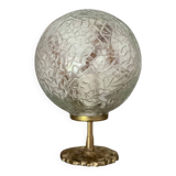 Small handcrafted globe lamp with a cracked finish and a golden brass base.