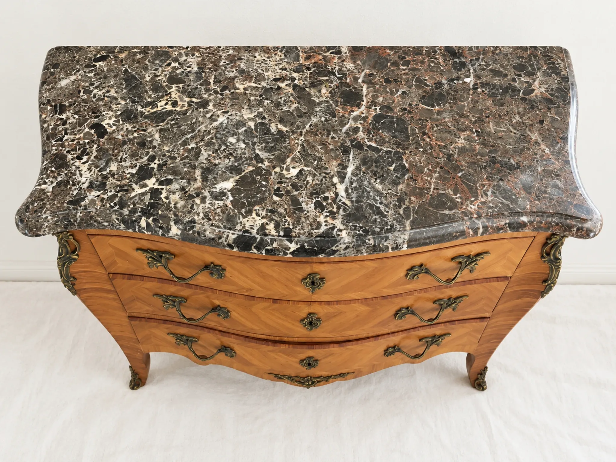 Curved Louis XV style commode in marquetry, veined marble and ornamentation.