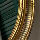 Oval-shaped wooden mirror in gold color