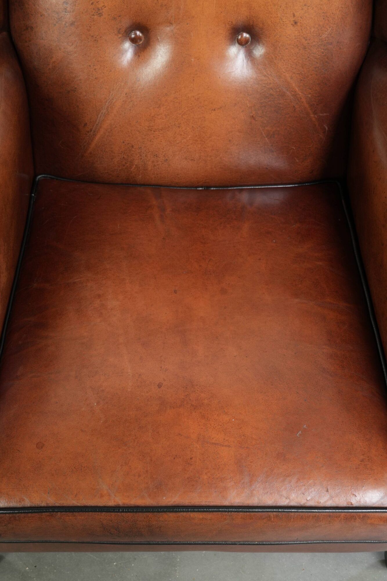 Sheepskin wingback armchair in a warm cognac colour with refined nailhead trim