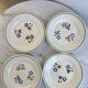 Set of 4 small flat plates with floral designs.