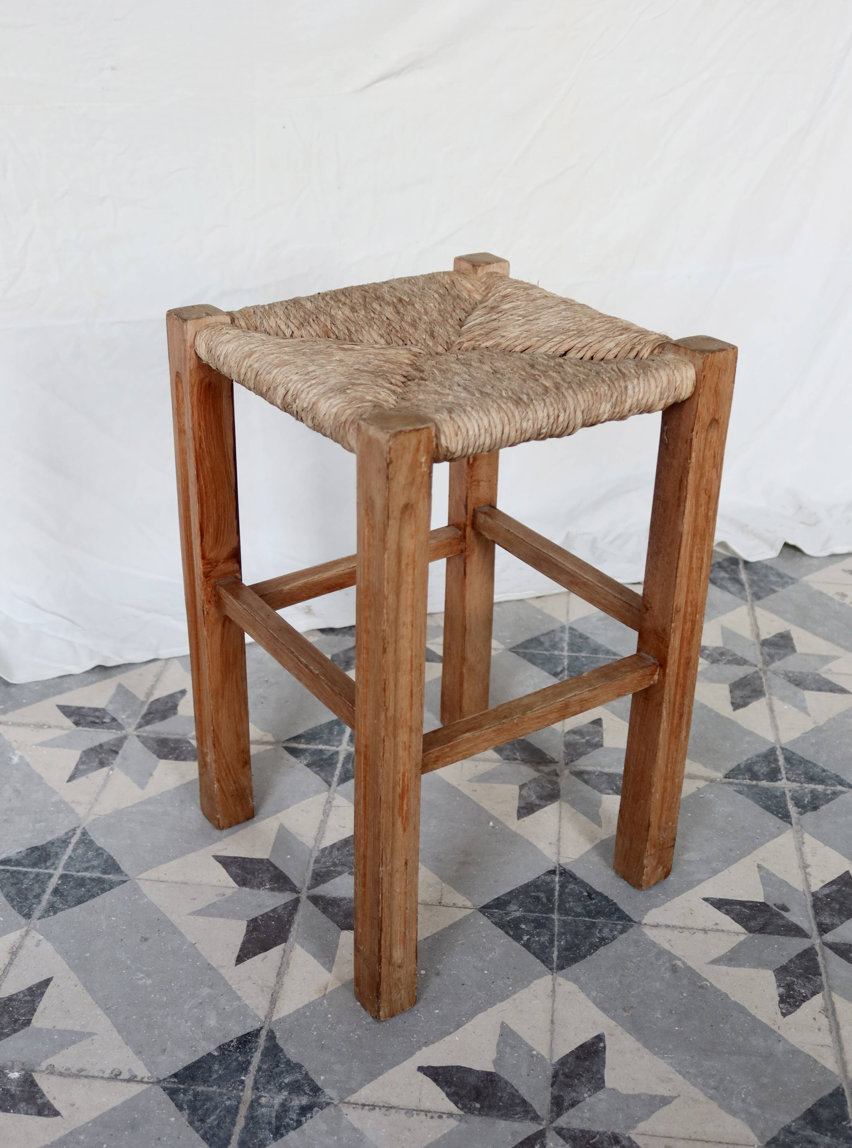 Vintage low stool in rustic style made of wood with a straw seat.