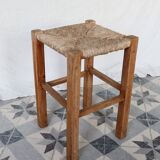 Vintage low stool in rustic style made of wood with a straw seat.
