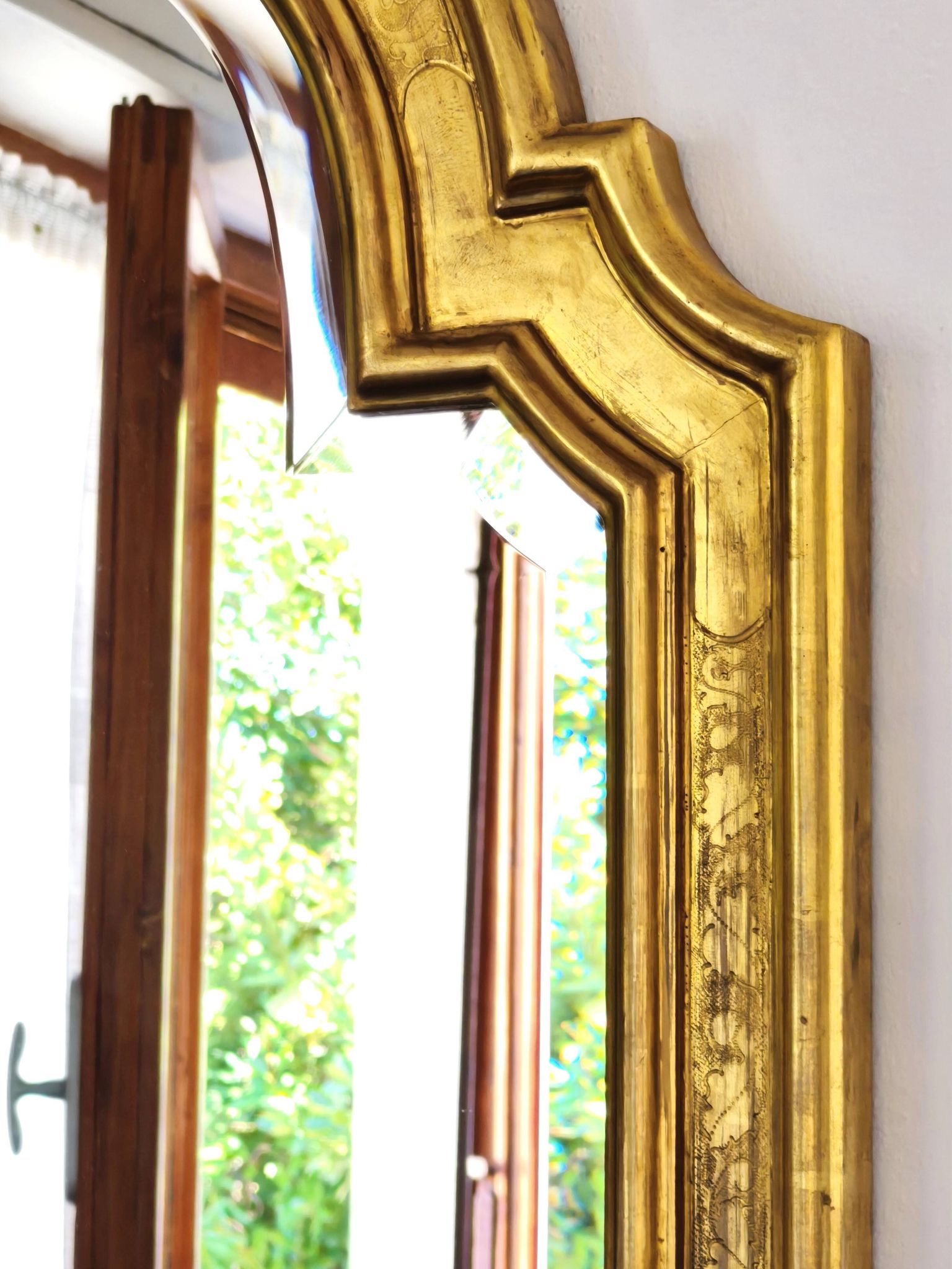 Florentine arched mirror in gilded wood with gold leaf.
