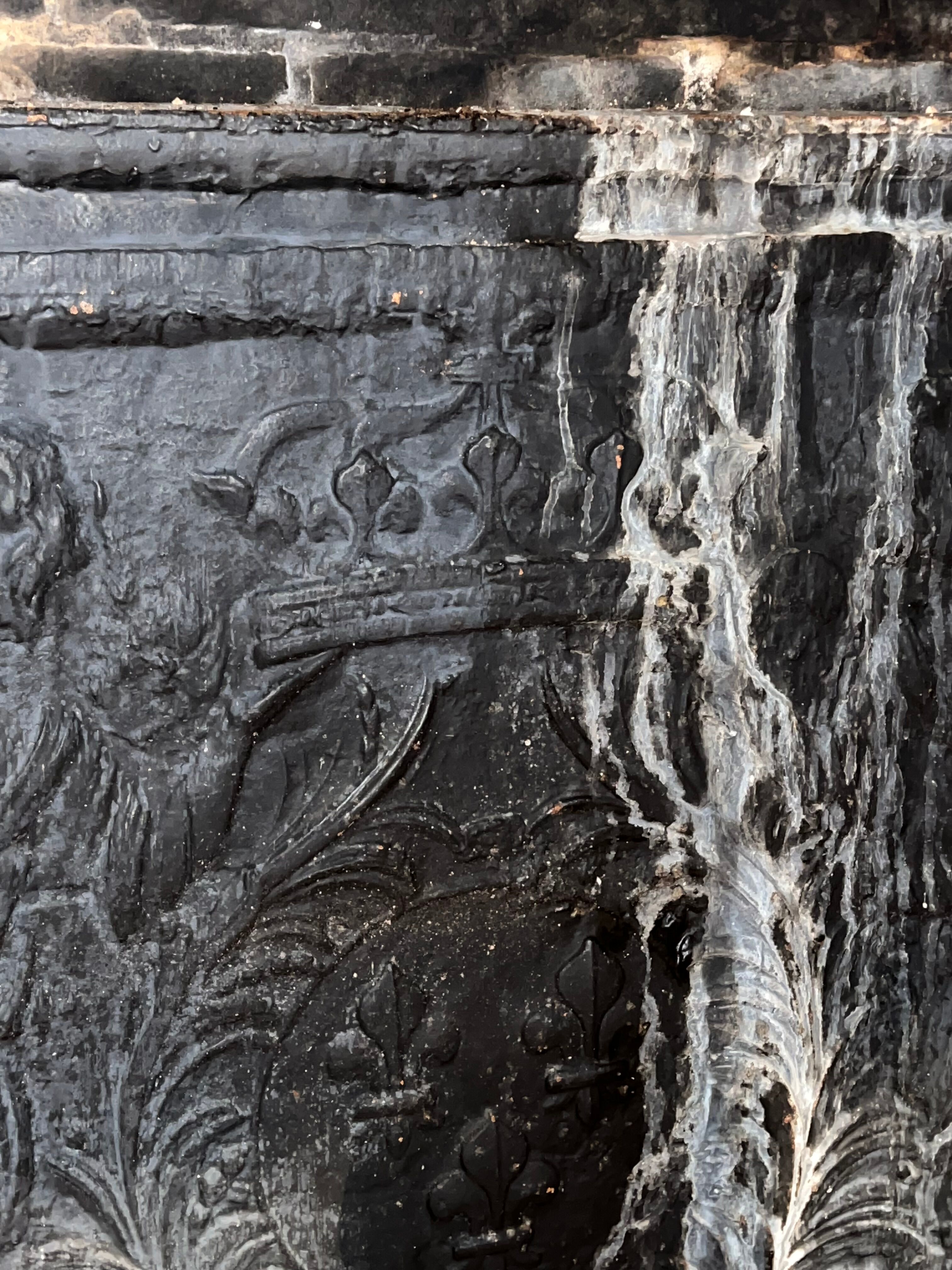 huge old fireplace plate has decoration of angels, crown and fleurs-de-lis