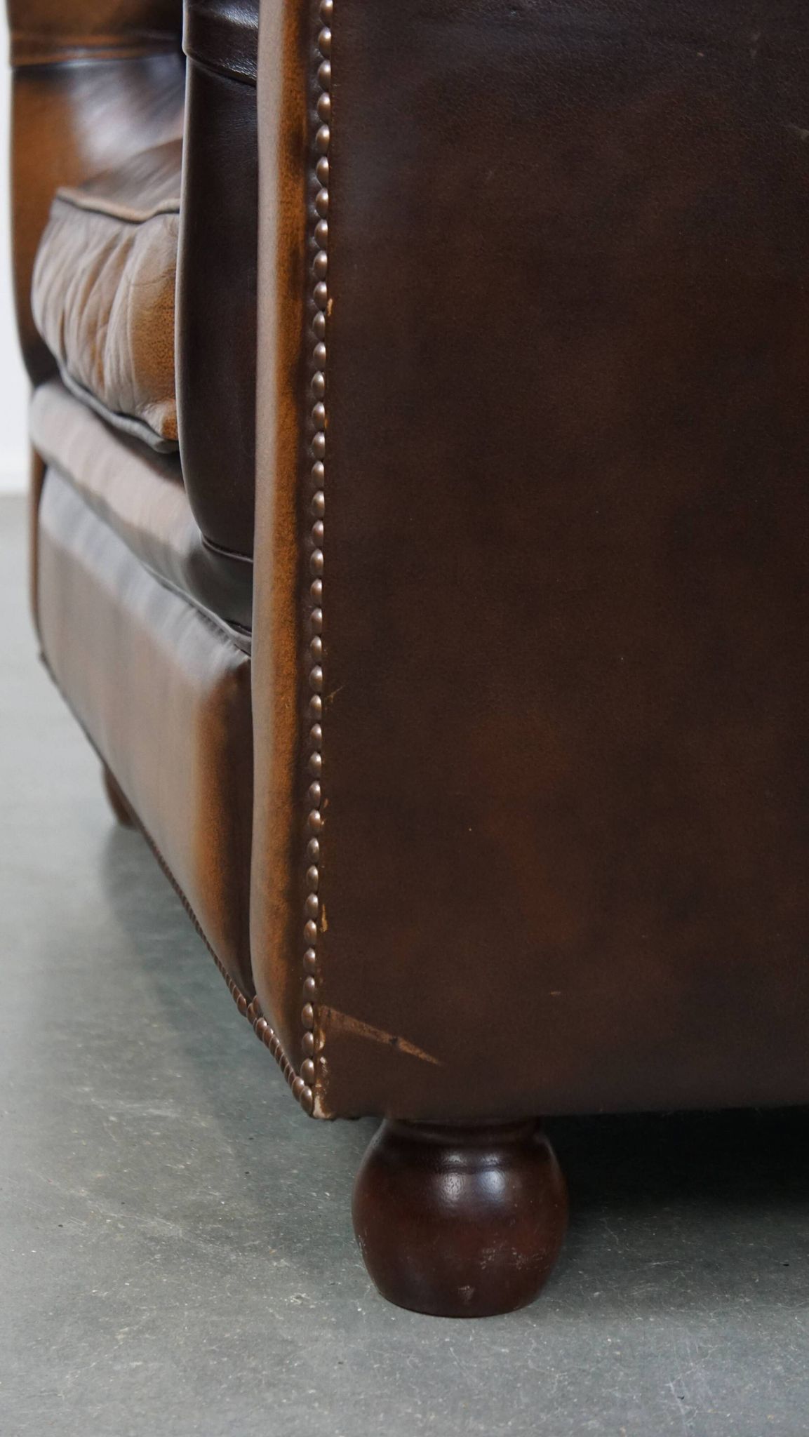 A well-maintained cowhide leather English Chesterfield armchair