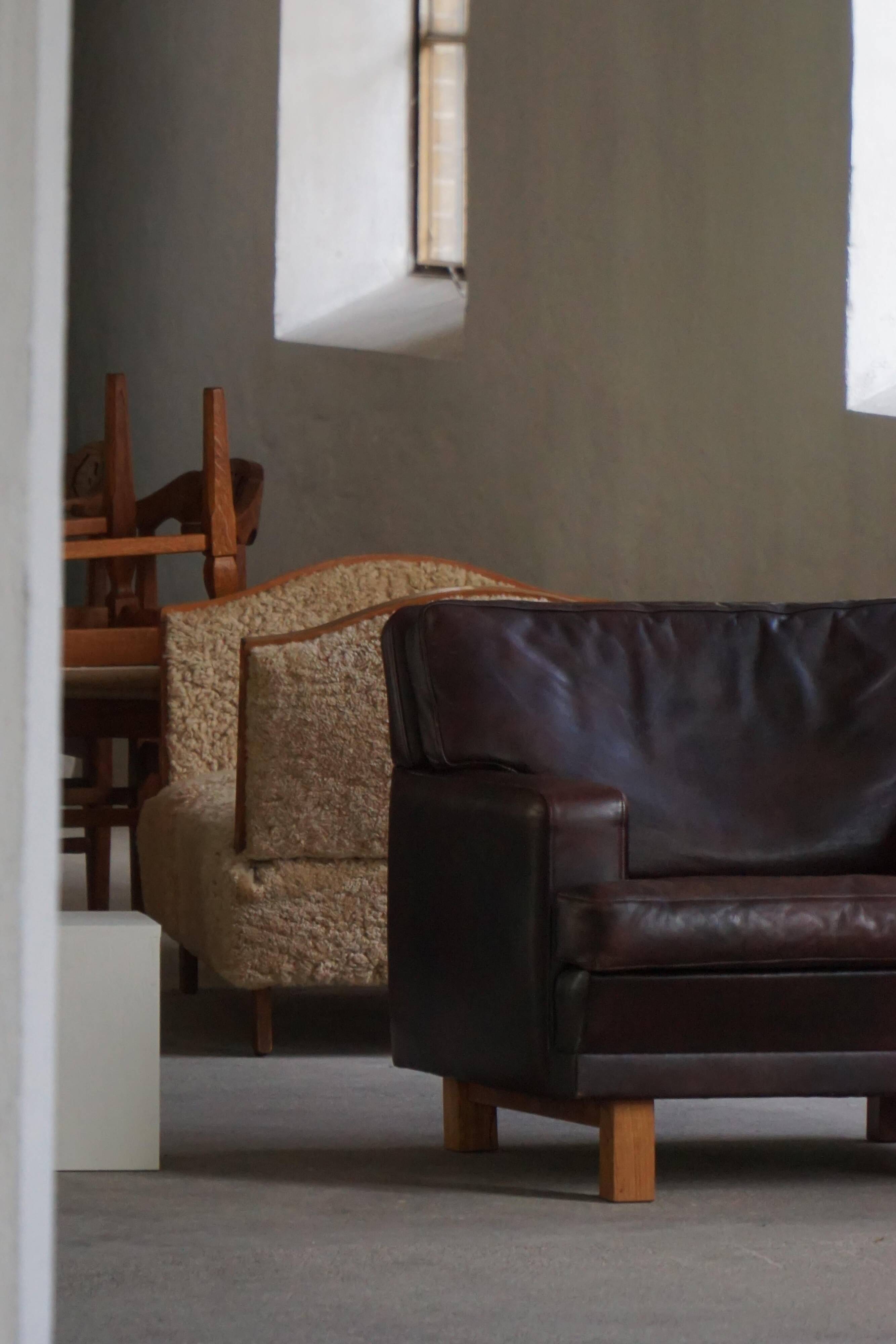 Pair of modern Danish lounge chairs in dark brown leather and rosewood, 1960s.