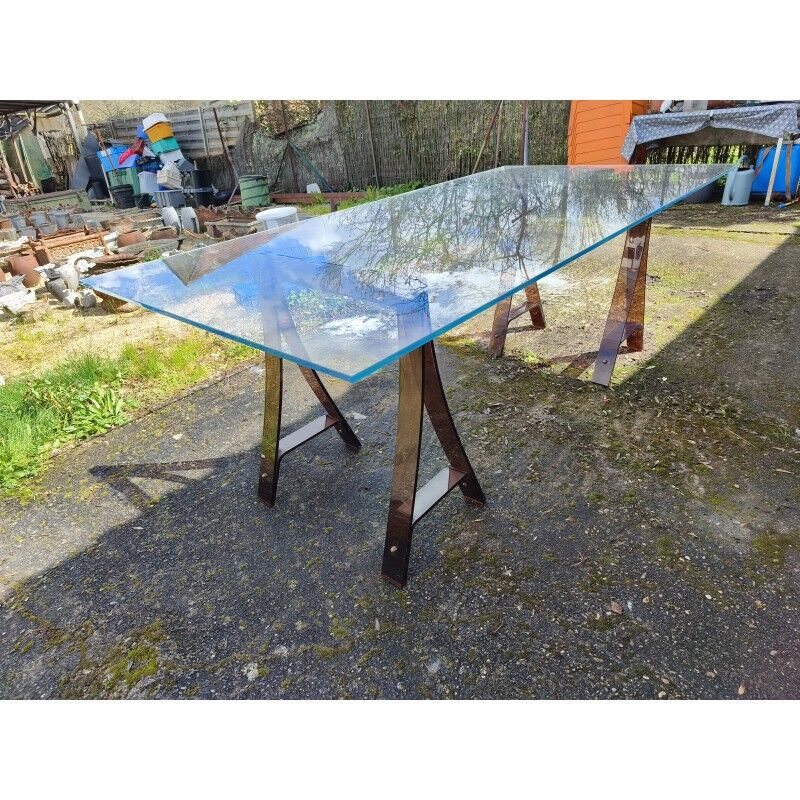 Vintage table with a glass top and smoked plastic trestle legs.