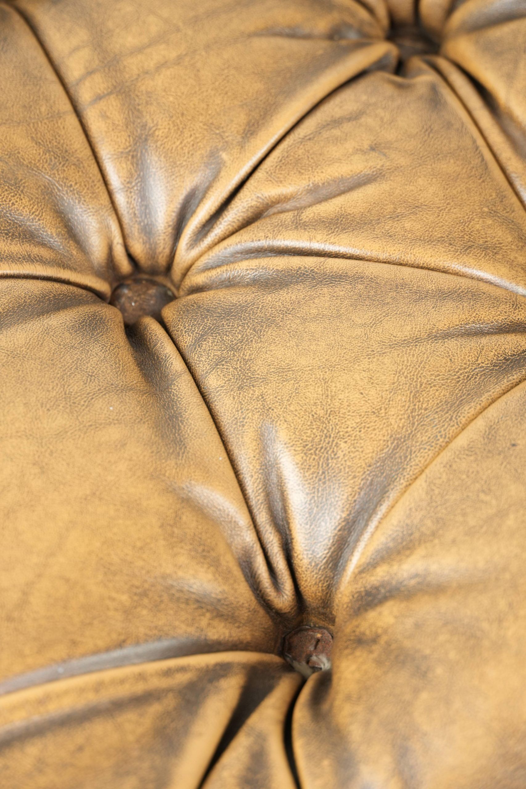 Ottoman chesterfield anglais en cuir élégant, fini avec des clous décoratifs.