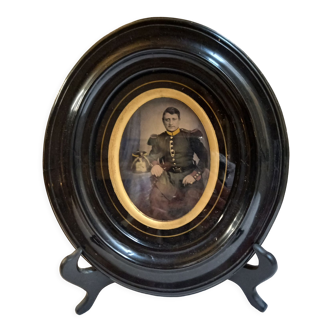 Old photograph recolorized of a soldier, under glass, painted wood frame, black and gold