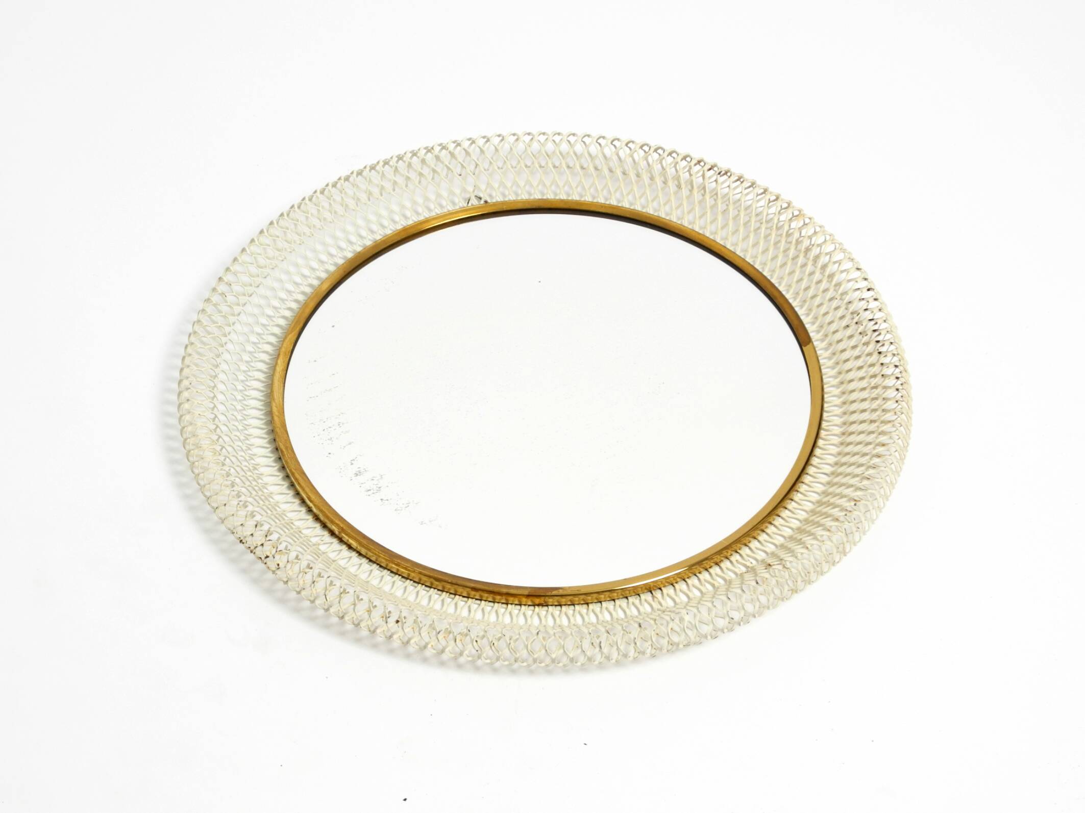 Mid Century Modern round wall mirror with a white expanded metal frame