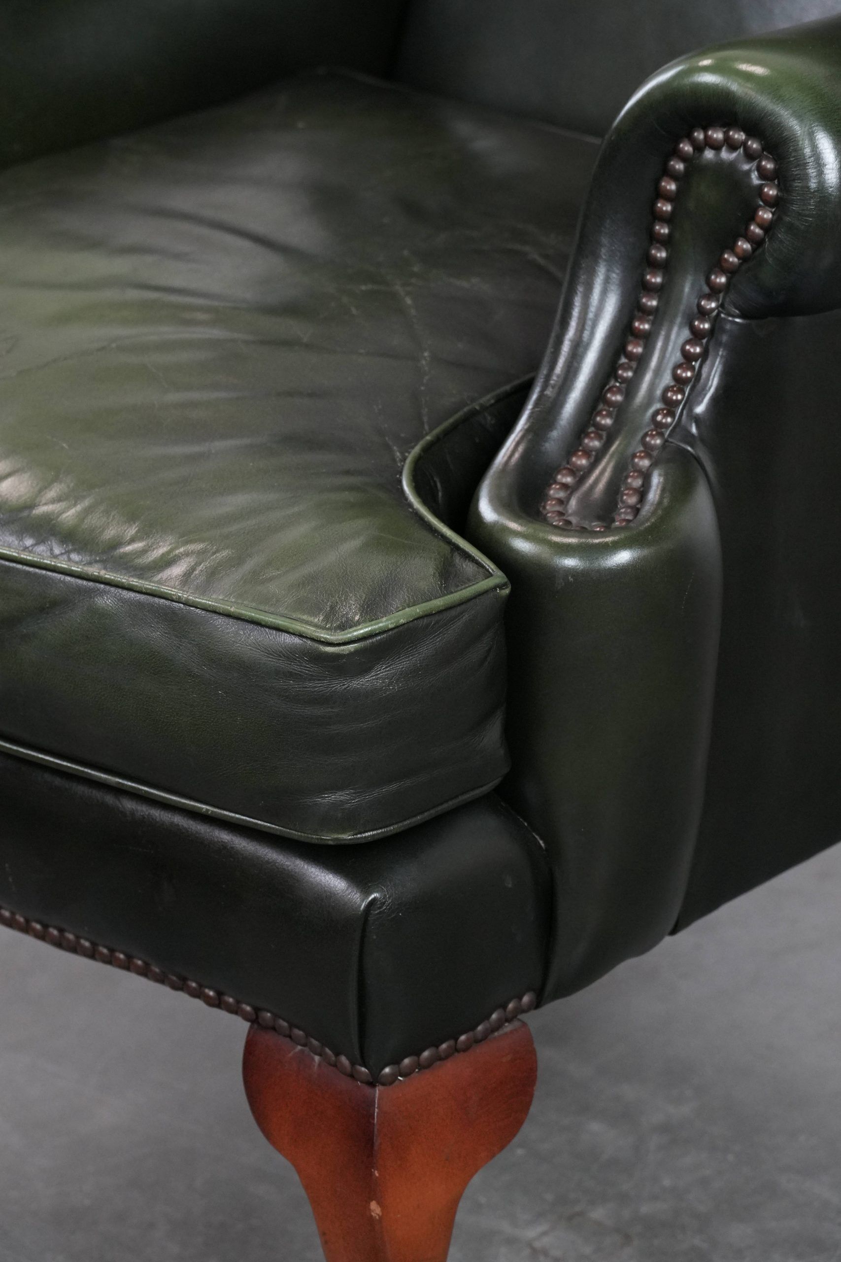 Smooth classic cowhide Chesterfield armchair in a stylish dark green color
