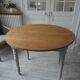 Raised walnut table with drop-leaf top, base on verdigris castors.