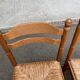 4 solid wood kitchen chairs with straw seats in a country farmhouse style.