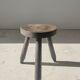 Small brutalistic tripod stool in dark wood tapered feet circular seat