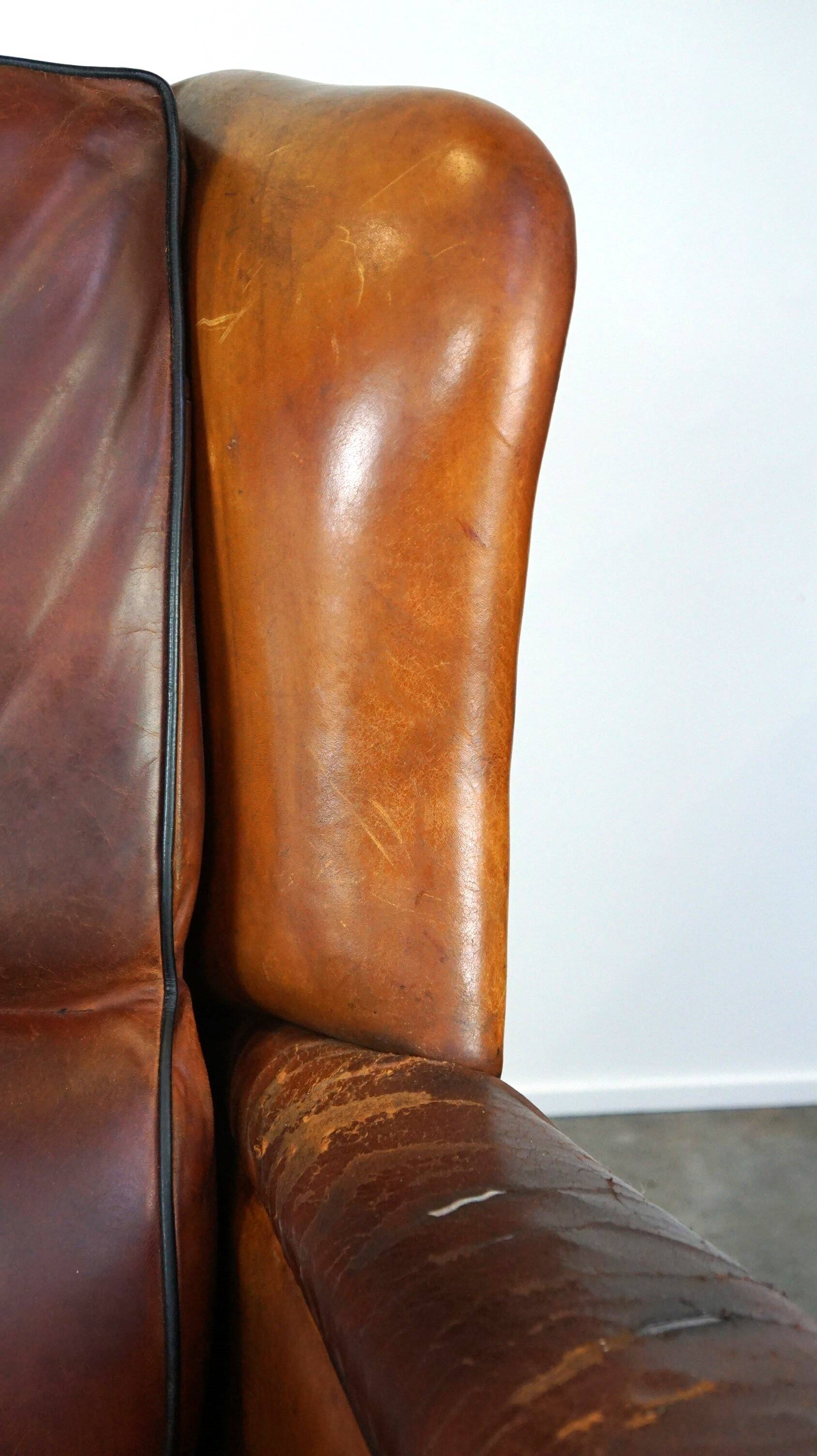 Very large worn sheepskin wing chair with a checked seat cushion