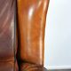 Very large worn sheepskin wing chair with a checked seat cushion