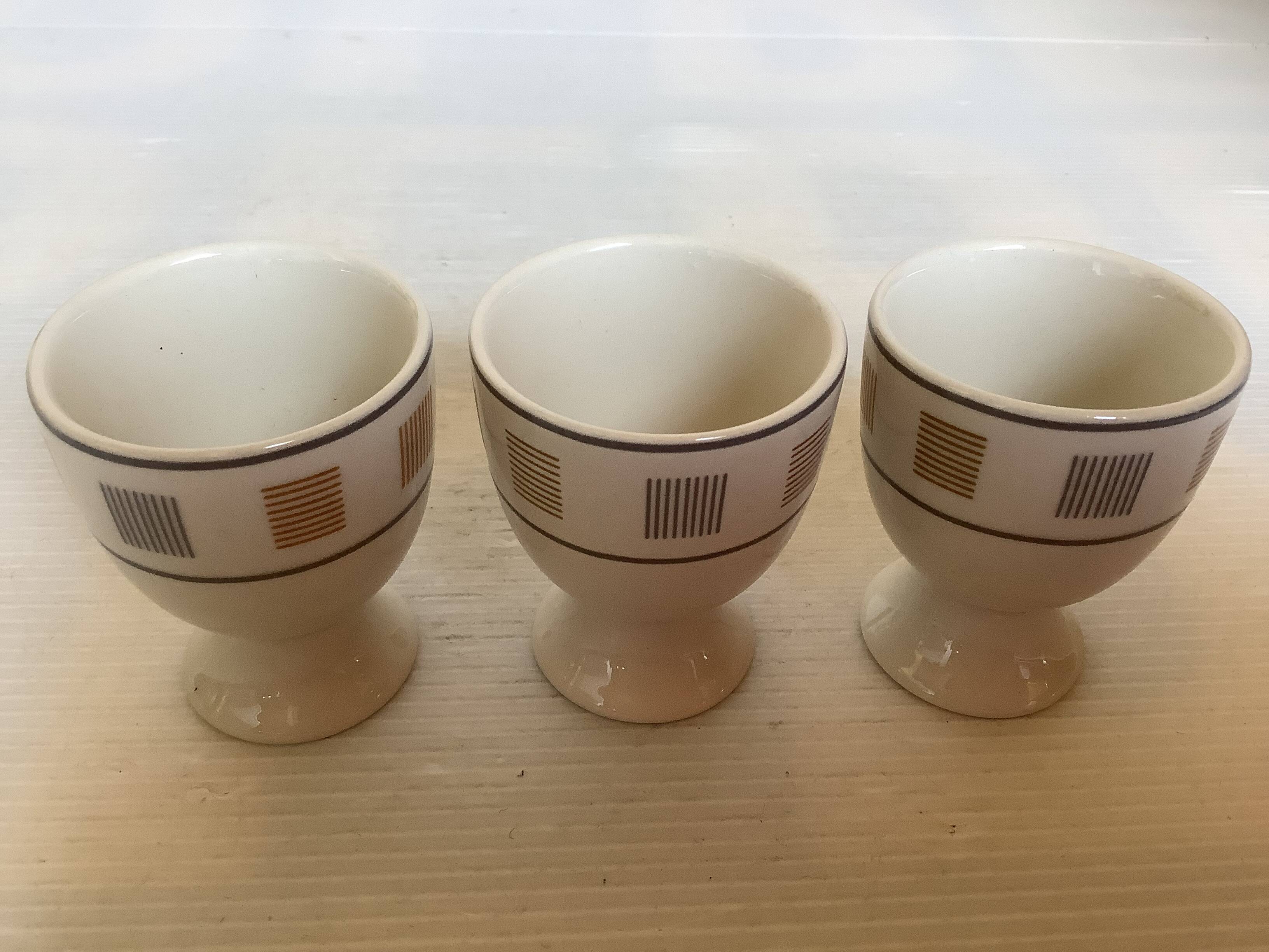 Three egg cups with geometric patterns in beige and brown.