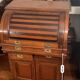 Antique solid wood secretary with a drop-down cylinder compartment.