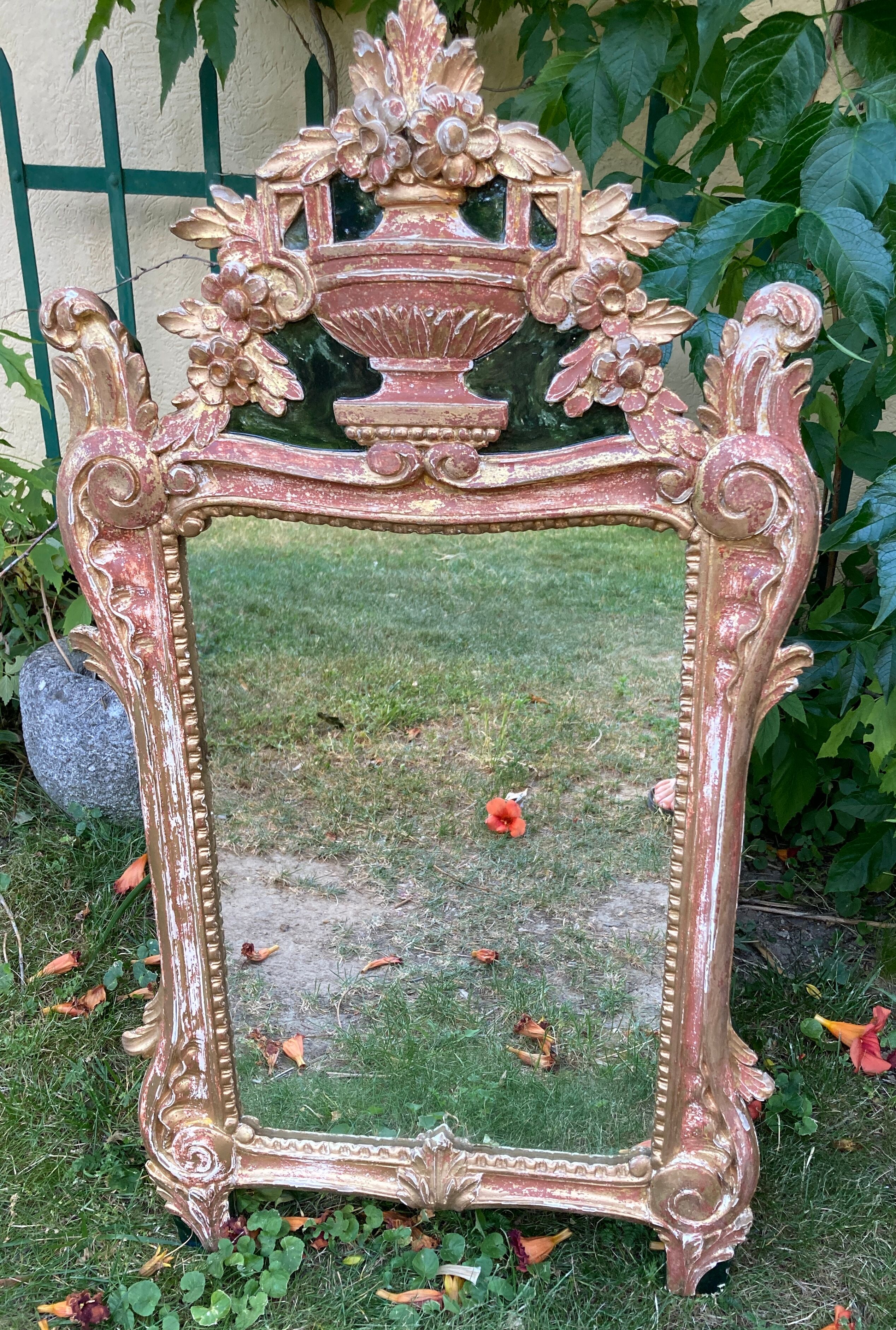 Mirror above a wooden and gilded stucco fireplace in the style of the 18th century.