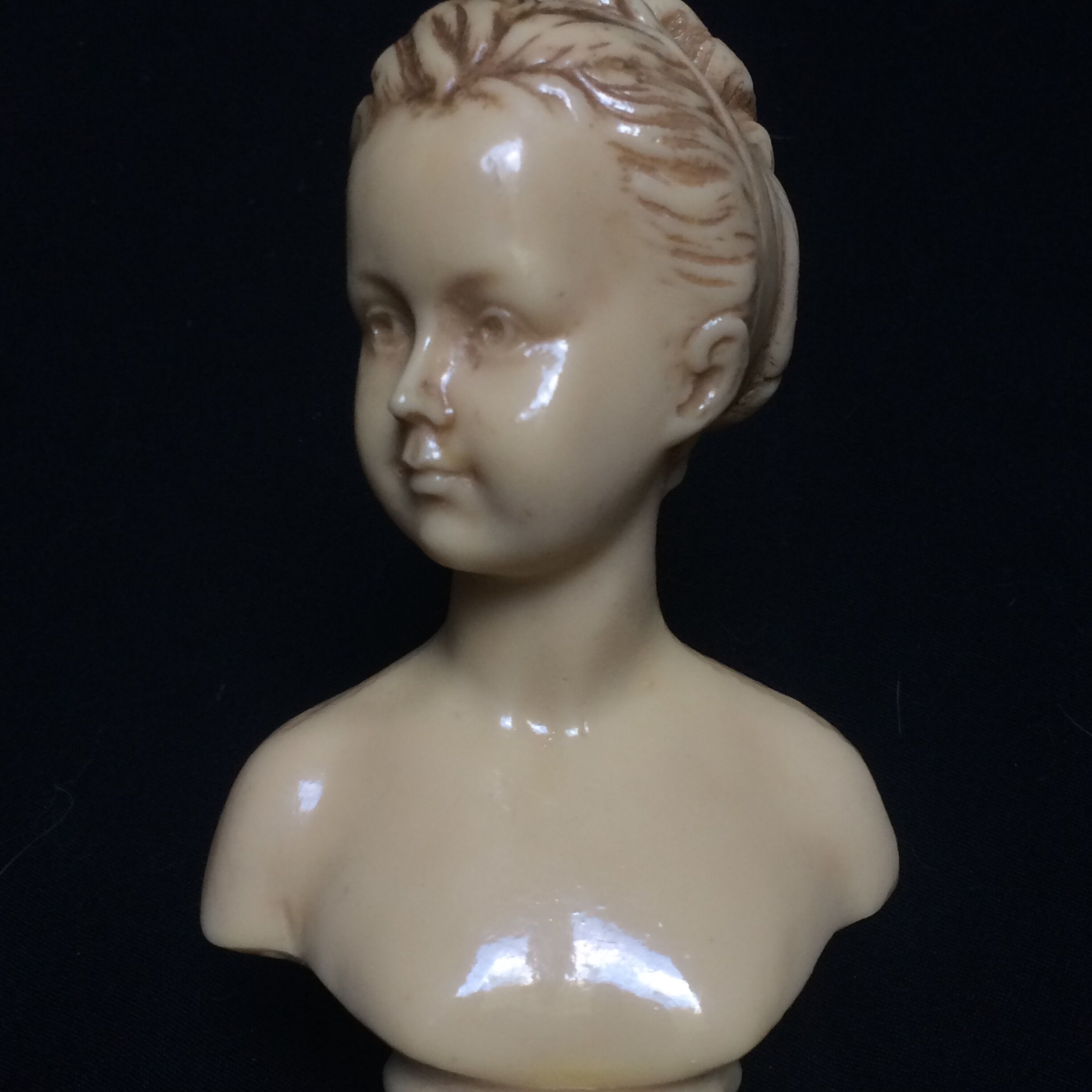 Bust in varnished dish, young girl with bun