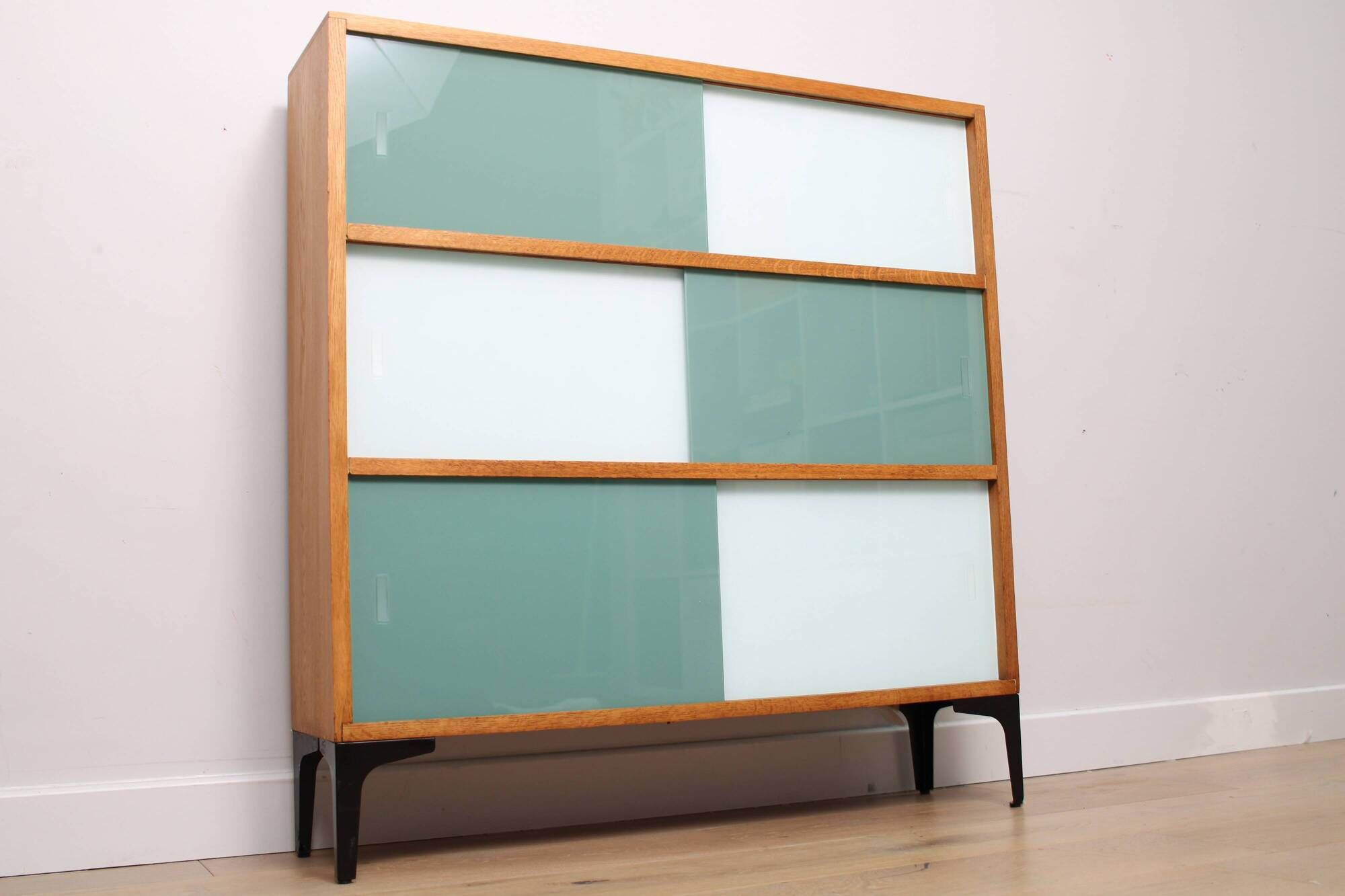 A vintage mid-century 3 tiered bookcase with glass sliding doors