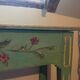 Old green wooden console with floral patterns.