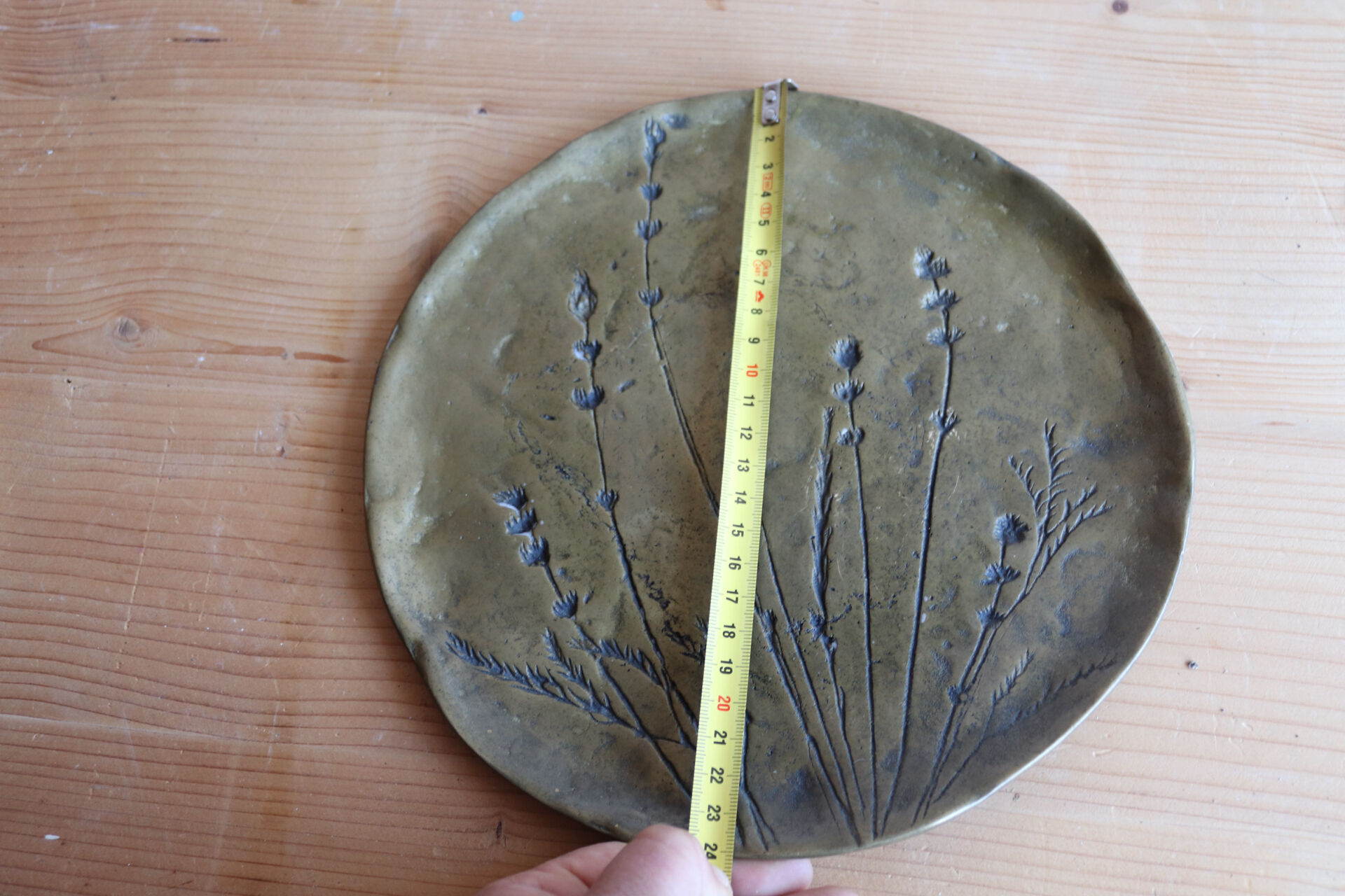 Decorative wall plaque in brass with a floral design.