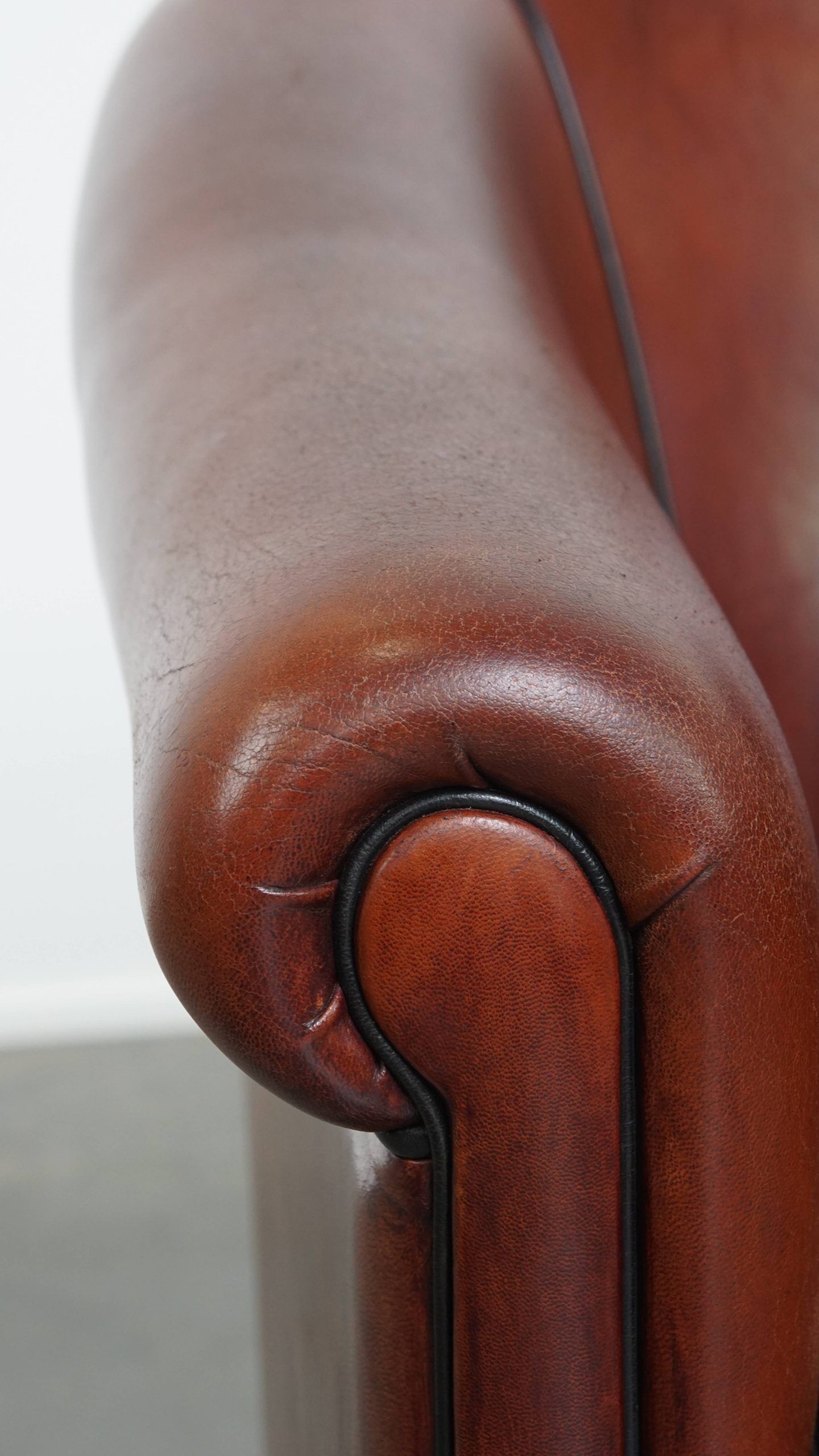 Sheepskin club armchair in a warm deep colour finished with black piping