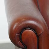 Sheepskin club armchair in a warm deep colour finished with black piping