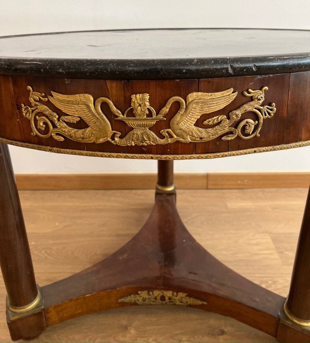 Empire gueridon in mahogany veneer adorned with chiselled and gilded bronze, topped with black marble with a groove.